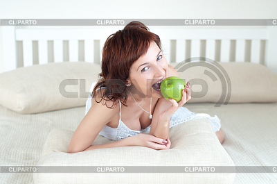 Atractiva mujer joven con una manzana verde en la cama | Foto de alta resolución |ID 3666207